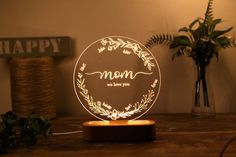 a personalized lamp with the word mom on it sits on a table next to a potted plant