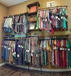 a room filled with lots of different colored shirts and ties hanging on the wall next to each other