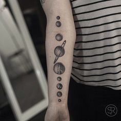 a person with a tattoo on their arm that has an image of the planets in it