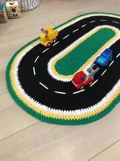 a crocheted rug with cars and trucks is on the floor in front of a child's play area