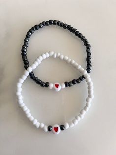 two black and white beaded bracelets with red heart beads on each one side