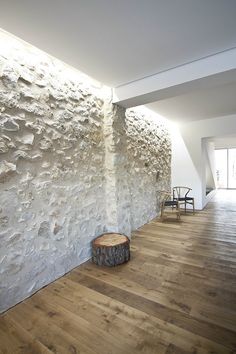 an empty room with wood flooring and stone wall in the background, there is a wooden stool next to it