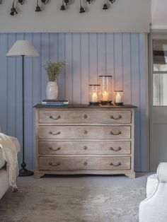 a dresser with candles on it in a living room next to a couch and chair