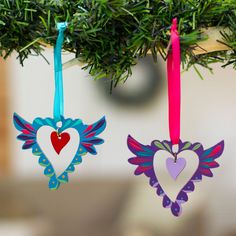 two heart shaped ornaments hanging from a tree