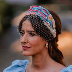 a woman wearing a birdcage veil on her head and looking off to the side