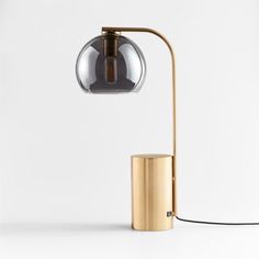 a lamp that is sitting on top of a metal stand next to a white wall