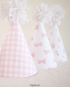 three paper party hats with pom poms on them