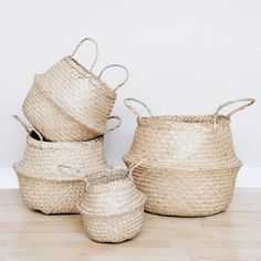 four woven baskets sitting on top of a wooden floor