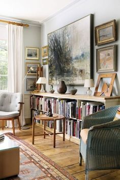 a living room filled with furniture and bookshelves next to a painting on the wall