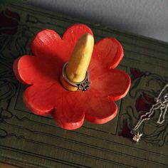 a red flower with a yellow object on it's end sitting on a table