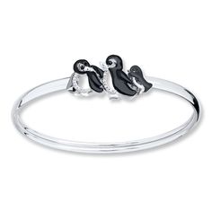 two black and white penguins sitting on top of each other in a silver bangle