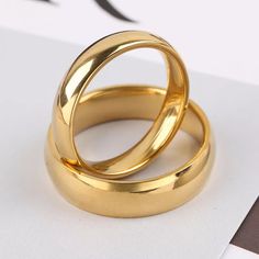 two gold wedding rings sitting on top of each other