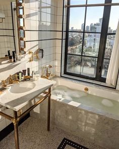 a bathroom with a tub, sink and large window overlooking the cityscape outside