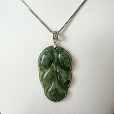 Jade Leaf Stone Type: Jadeite Jade (Untreated Grade A) Pendant Size: 1.55 x 0.92 x 0.20 in. Pendant Weight: ~8 g Unique ID: GDTC-* NATURAL JADE: Crafted from natural untreated jadeite jade (Grade A). PENDANT: Beautifully crafted leaf jade pendant with sterling silver bail. JADE COLOR: Green CHAIN NECKLACE: Comes with an 18'' Sterling Silver Chain. GIFT BOX: Comes with a gift box. Perfect for gifts! MINOR IMPERFECTIONS: This piece is hand carved and completely natural. It may have small imperfections from the natural stone or hand carving art. Depending on your lighting, monitor screen, or phone screen the stone may look slightly different in color. Jade Oval Pendant With Natural Stones, Jade Oval Pendant Necklace With Natural Stones, Jade Necklace With Oval Pendant And Natural Stones, Oval Jade Jewelry With Natural Stones, Jade Pendant For Jewelry Making, Jade Gemstone Pendant Jewelry, Baby Buddha, Bull Cow, Lucky Symbols