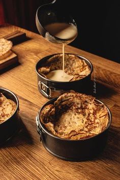 three pans filled with food sitting on top of a wooden table next to each other