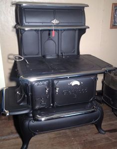 an old fashioned black stove sitting on top of a wooden floor