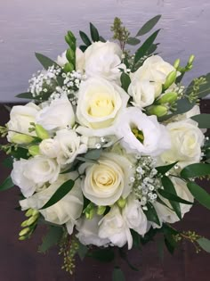 a bouquet of white flowers and greenery on a table