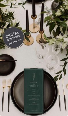 the table is set with black plates, silverware and greenery for an elegant dinner