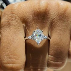 a person's hand with a diamond ring on top of their thumb and fingers