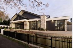 a modern house with stone and black accents on the front, fenced in yard