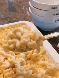 a spoon full of macaroni and cheese is being lifted from a casserole dish