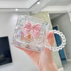 a person holding up a clear glass case with a pink bow on it's side