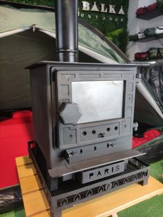 a black stove top oven sitting on top of a wooden table next to a tent