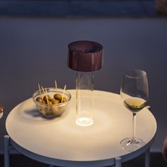 a table with two wine glasses and some olives in a bowl next to it