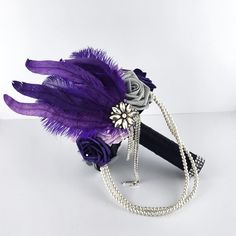 a bridal bouquet with purple feathers and pearls on the headband, sitting on a white surface