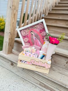 a wooden box filled with assorted items on top of a set of steps next to flowers