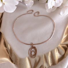 a close up of a bracelet on a table with flowers in the background and a gold cloth draped around it