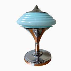 a blue glass lamp sitting on top of a metal stand