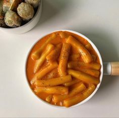 a white bowl filled with carrots next to a bowl of macaroni and cheese