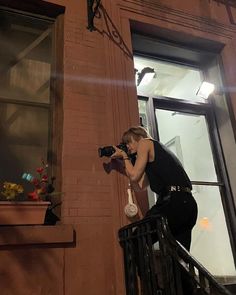 a woman is taking a photo on the balcony of a building at night with her camera