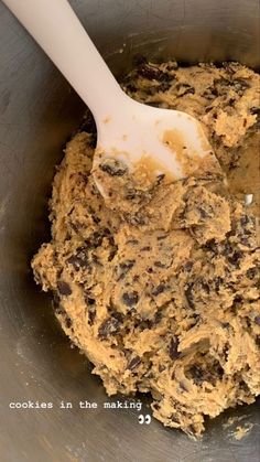 a mixing bowl filled with batter and chocolate chip cookies in the making process, ready to be mixed together