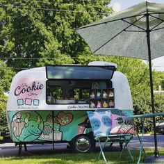 an ice cream truck is parked on the side of the road with two lawn chairs and an umbrella