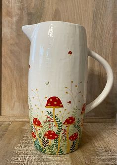 a white pitcher sitting on top of a wooden table