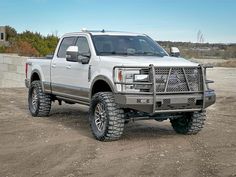 a large white truck parked on top of a dirt field