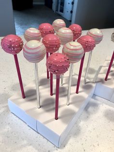 there are many pink and white cake pops on display