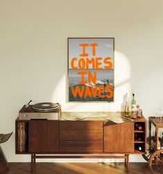 a record player sitting on top of a wooden cabinet in front of a poster that says it comes in waves