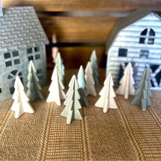 small paper christmas trees in front of a barn and silo on a brown table