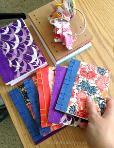 a person is holding an item in their hand near many different colored papers on a table