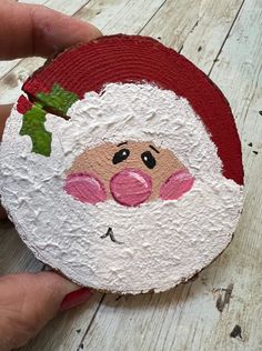 a hand holding a painted santa clause ornament