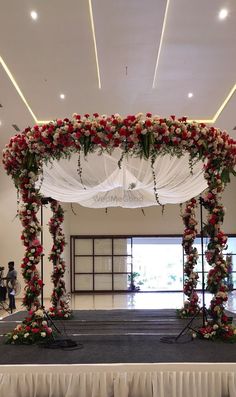 a white and red wedding arch with flowers on the top is set up for an event