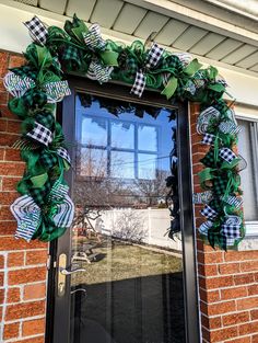 the front door is decorated with green and black plaid ribbon wreaths for st patrick's day