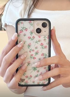 a woman holding up her phone case with pink flowers on the back and white background