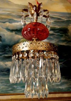 a chandelier hanging from the ceiling in front of a painting with water and clouds