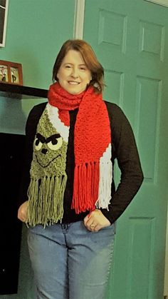 a woman standing in front of a green door wearing a red and white scarf with an angry face on it