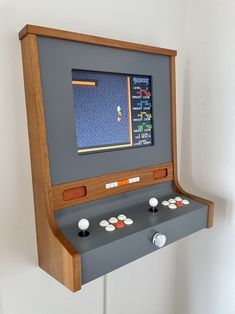 an old fashioned video game with buttons and controls on the front, mounted to a wall