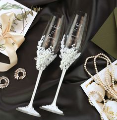 two champagne flutes are sitting on a table with pearls and other items next to it